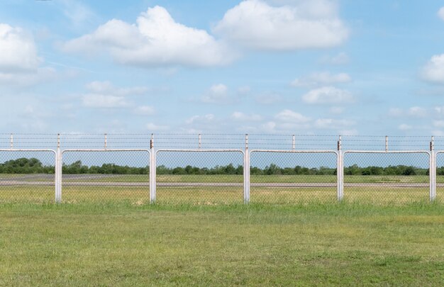 Photo field with green grass and metal fence