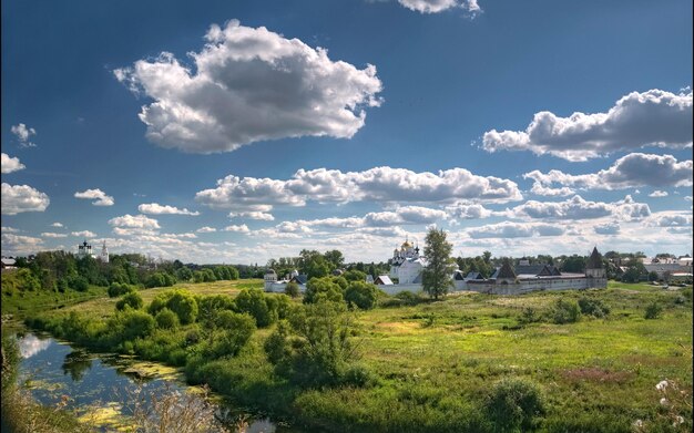 a field with a river and a few clouds in the sky