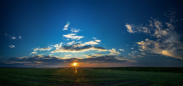 Fields farmland with blue cloudy sky in the evening time Field in the amazing beautiful colorful summer sunset Beautiful thunder clouds over the field