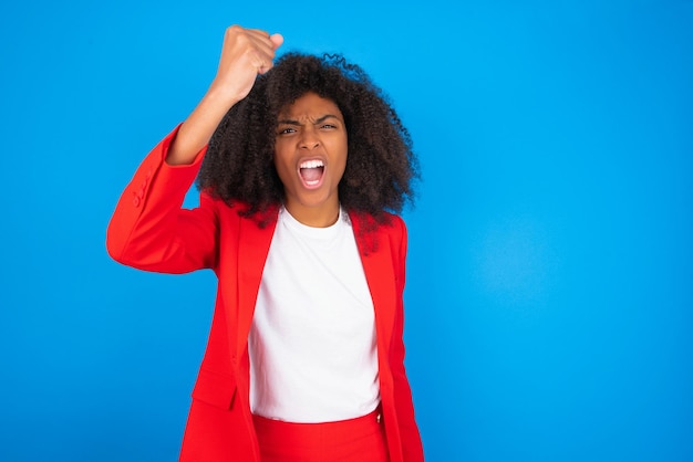 Fierce woman holding fist in front as if is ready for fight or challenge screaming