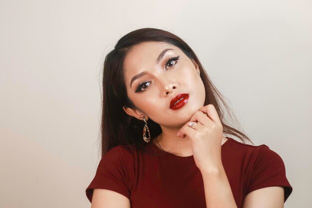 A fiercelooking Asian woman in a red shirt posing in front of white background