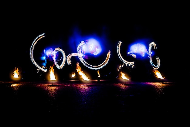 Fiery pieces of a fire show against a dark sky and thunderstorms