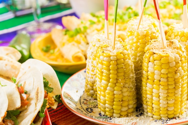 Fiesta feestbuffettafel met pittige Mexicaanse maïskolven en ander traditioneel Mexicaans eten.