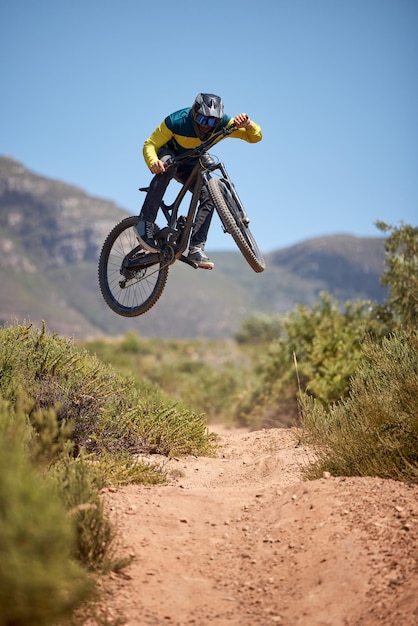 Fiets bmx en fitness met een mannelijke motorrijder op een onverharde weg of baan een sprong maken met een mountainbike luchtnatuur en fietsen met een mountainbiker die in de lucht springt terwijl hij buiten rijdt voor adrenaline