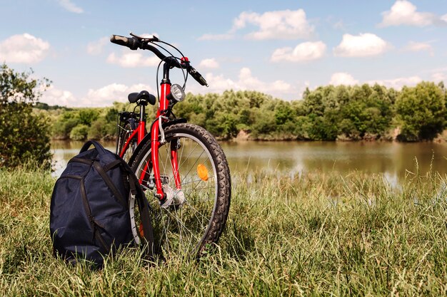 Fiets en rugzak op het gras op de achtergrond van het meer