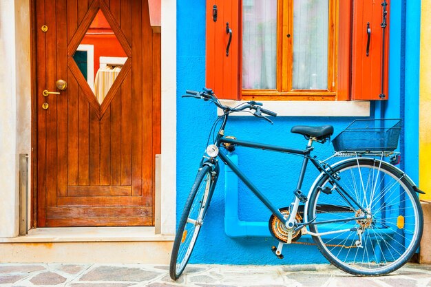 Fiets geparkeerd in de buurt van het blauwgeverfde huis kleurrijke architectuur op het eiland burano, venetië, italië