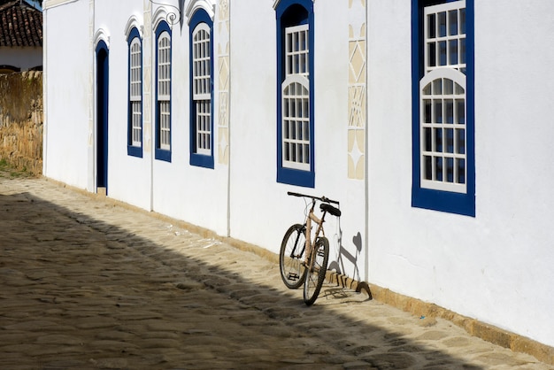 Fiets geparkeerd naast de witte muur met blauwe ramen