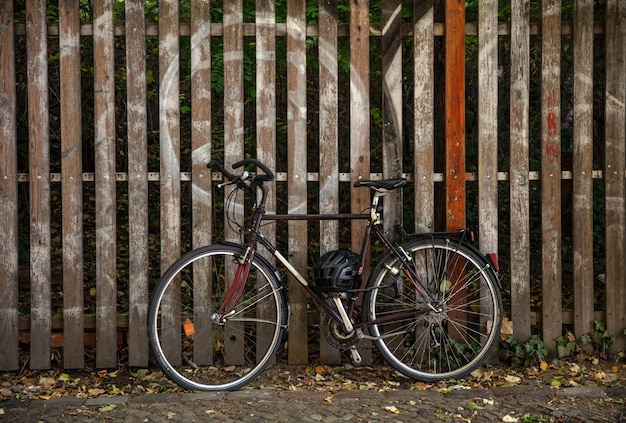 Fiets geparkeerd tegen houten hek en zwart veiligheidshelmbehang