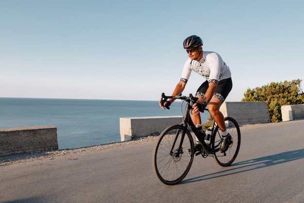 Fietsen sport atleet man rijden op kustweg bij dageraad