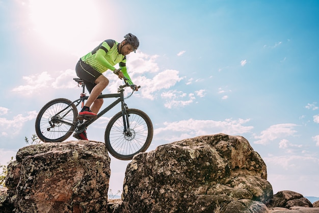 Fietser die de fiets berijdt onderaan de rots in Berg. Extreme sport en enduro fietsen concept.