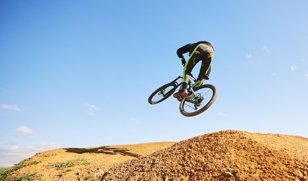 Fietser en spring in de lucht, vuil en buiten voor sportrace of avontuur in zomerbos of natuur Extreem fietsende persoon en vrijheid voor trail-mockup-ruimte of uitdaging voor fitness in het bos