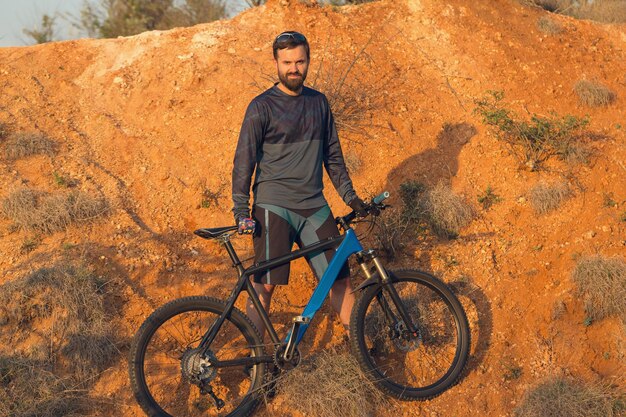 Fietser in broek en fleecejack op een moderne carbon hardtail-fiets met een luchtgeveerde vork De man op de top van de heuvel rijdt op een fiets