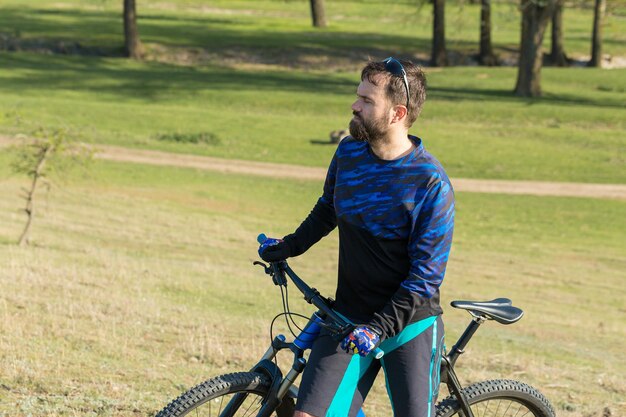 Fietser in broek en fleecejack op een moderne carbon hardtail-fiets met een luchtgeveerde vork De man op de top van de heuvel rijdt op een fiets