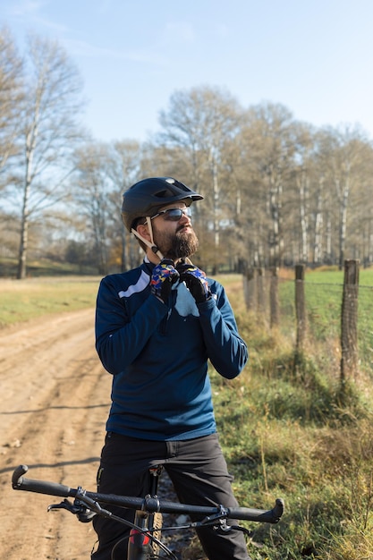 Fietser in broek en fleecejack op een moderne carbon hardtail-fiets met een luchtgeveerde vork rijdt offroad De man rust op een bankje in het herfstpark