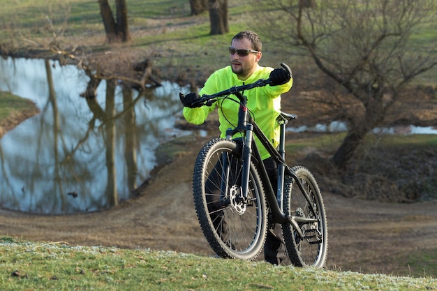 Fietser in broek en groene jas op een moderne carbon hardtail fiets met luchtgeveerde voorvork