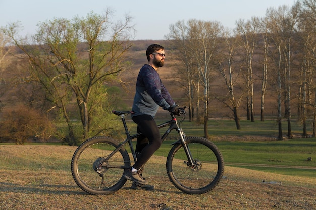 Fietser in korte broek en jersey op een carbon hardtail-fiets met een verende voorvork die op een klif staat