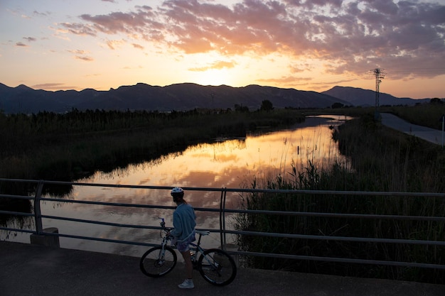 Fietser kijkt naar de rivier bij zonsondergang