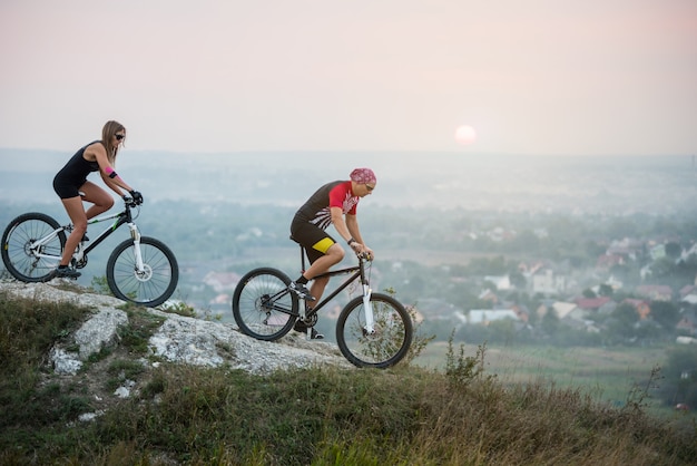 Fietser met vriendin in beweging op sportfietsen op de achtergrond van de prachtige zonsondergang.