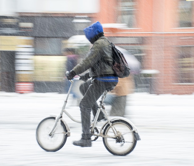 Fietser op de weg van de stad in een besneeuwde dag in bewegingsonscherpte. onscherpe afbeelding