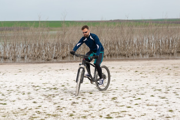 Fietser op een mountainbike op een zoutstrand op een achtergrond van riet en een meer