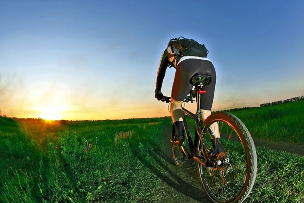 Fietser rijdt op de weg naar de zonsondergang