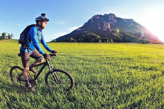 fietser rijdt op een fiets op het groene veld naar de zon