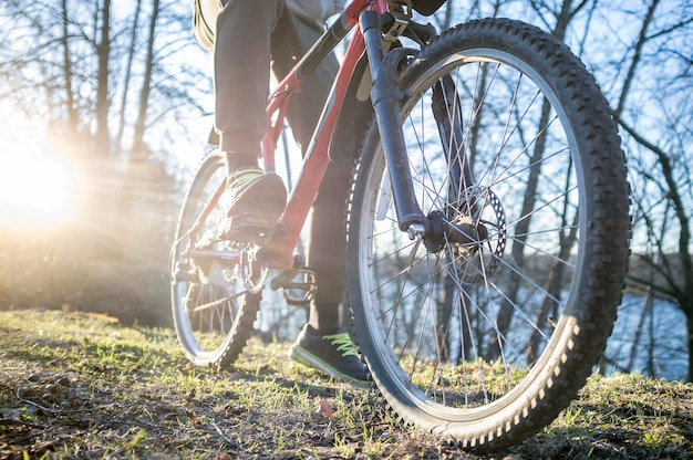 Fietser rust na een rit langs de oevers van de rivier, lenteavond in de ondergaande zon.