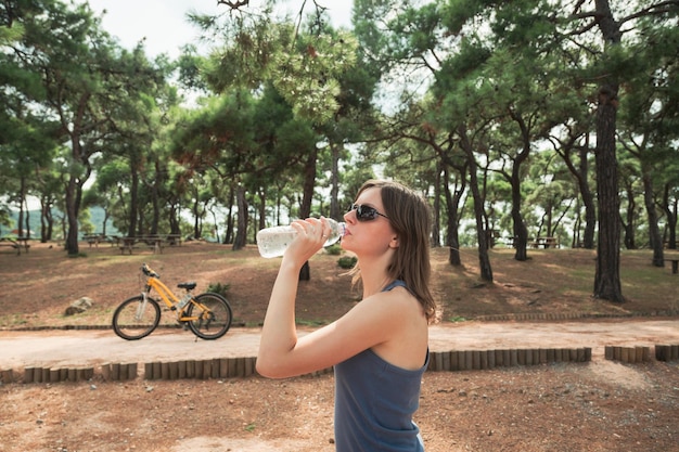 Fietser vrouw drinkwater in de buurt van de fiets in een openbaar park