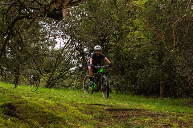 Fietser vrouw met helm en bril op haar fiets in het midden van een bos