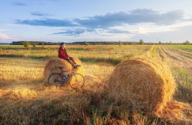 Fietser zit op een hooiberg na een fietstocht bij zonsondergang Actieve levensstijl en reisconcept