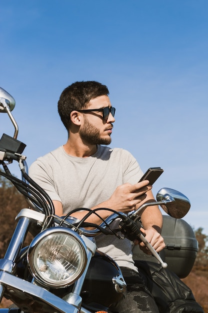 Fietser zittend op de motorfiets en maakt een foto van het landschap met de mobiel