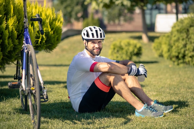 Fietser zittend op het gras in de buurt van de fiets