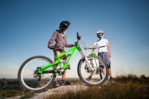 Fietsers met mountainbikes op de heuvel onder de blauwe hemel