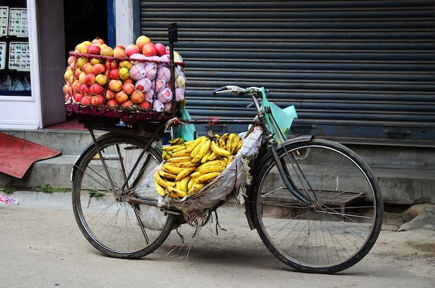 Fietskar-venter van nepali man-verkoper stop op wegverkoop verschillende soorten fruit en voedsel aan Nepalese mensen en buitenlandse reizigers kopen eten drinken op straatbazaarmarkt in de oude stad van Thamel in Kathmandu, Nepal