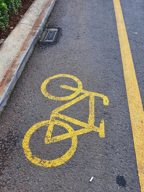 Fietspad bord in geel met ononderbroken lijnen op asfaltweg in Indonesië