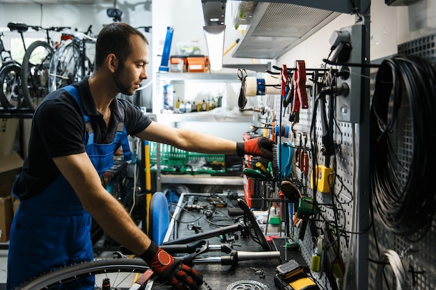 Foto fietsreparatie in werkplaats, man neemt gereedschap uit de plank