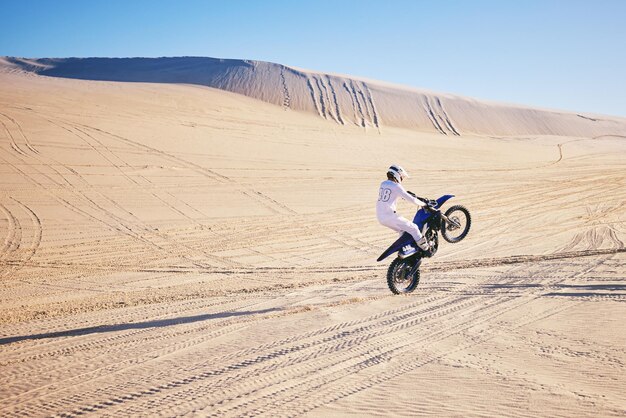 Fietssport en ruimte met een man in de woestijn voor adrenaline-avontuur of training in de natuur Moto-fitness en vrijheid met een atleet op een motorfiets voor energie of balans op zand in Dubai