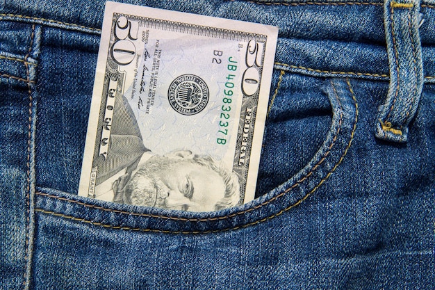 Fifty American dollars bill in the pocket of blue jeans