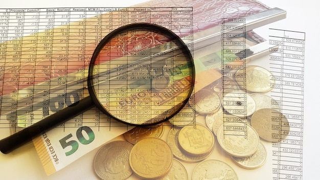 Fifty euro bill and coins magnifying glass on financial report double exposure Business finance and money concept