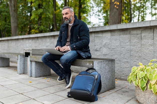 Fifty year old man working on laptop in the park