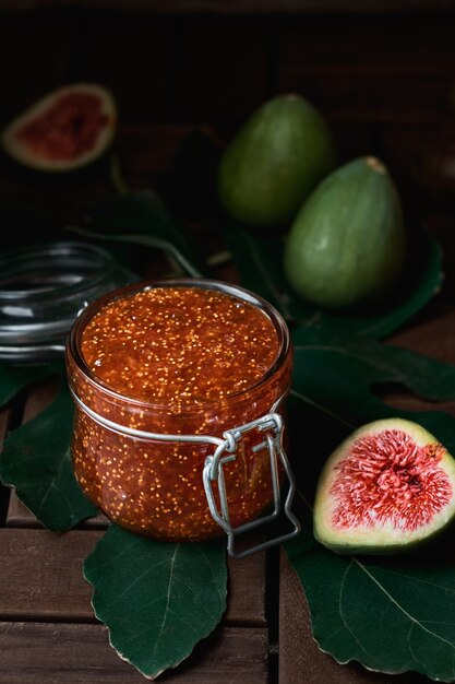 Fig jam in a glass jar, next to a half of a fresh fig