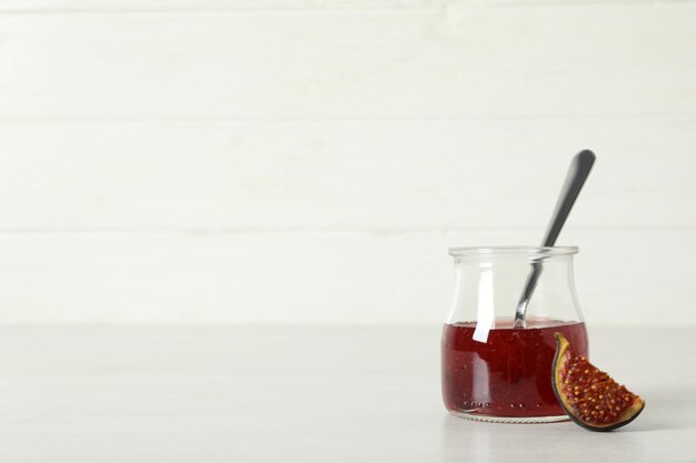 Photo fig jam in jar spoon and piece of fig on white background space for text