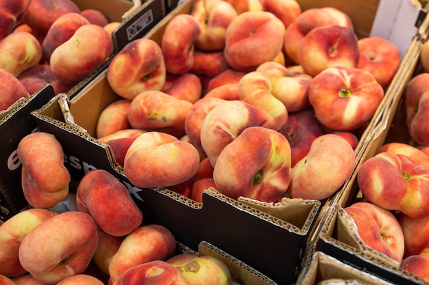 Fig peach, flat peaches in paper box at farmer's market or grocery shelves. Top view, diagonal view, background for agriculture purpose