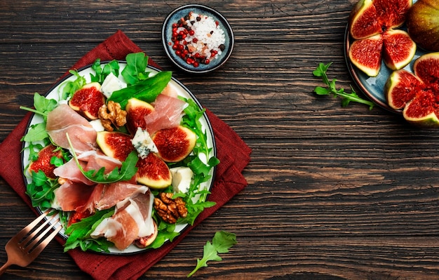 Insalata di fichi con prosciutto e formaggio blu noci rucola su sfondo di legno vecchio vista dall'alto spazio copia