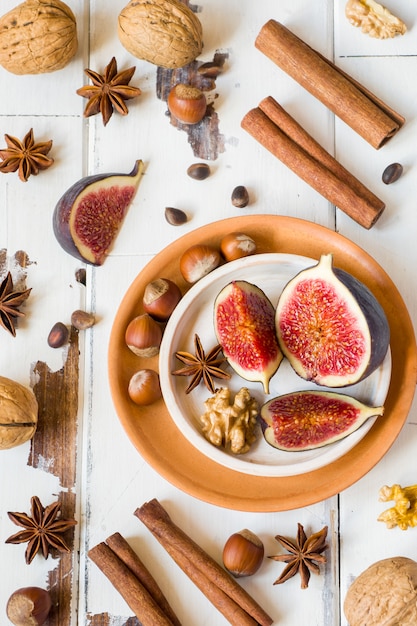 Fig walnuts cinnamon anise on a plate of old wooden surface.