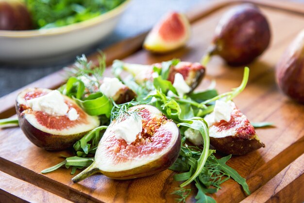 Foto fichi con caprino e rucola su tagliere in legno