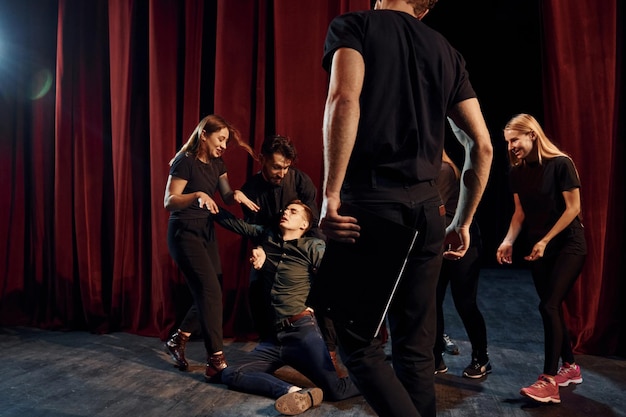 Photo fight scene group of actors in dark colored clothes on rehearsal in the theater