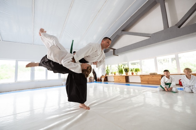 Fight time. Blonde-haired girl in white kimono having fight with her professional trainer