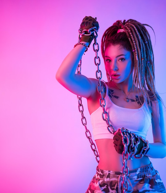 A fighter girl with chains on her hands with beautiful dreadlocks on her head in neon light