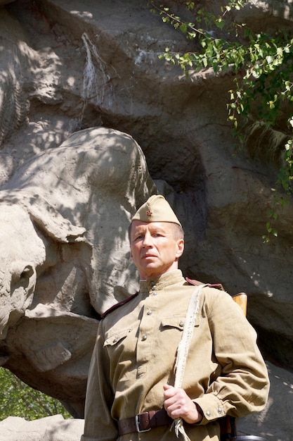 Fighter of Red Army in the form of times of World War II with the machine gun at a historical monument (fragment)